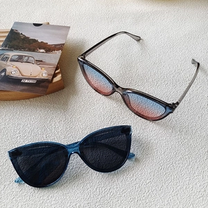 Close-up of translucent cat-eye sunglasses with gradient lenses on a minimalist background