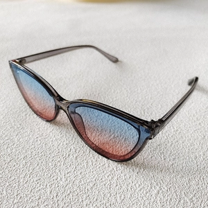 Detail of cat-eye sunglasses featuring blue-pink gradient lenses and grey frames