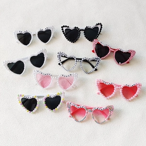 Detail of heart-shaped party sunglasses with assorted colors, pearls, and rhinestones