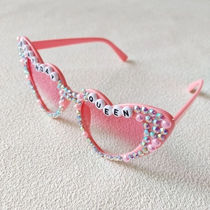 Detailed view of heart-shaped sunglasses with Birthday Queen lettering and pink rhinestones