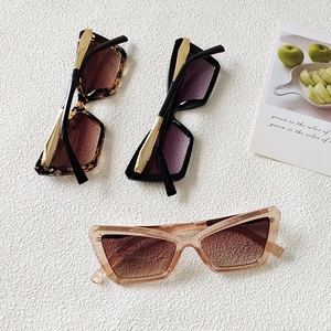 Detail of cat-eye sunglasses with gold metal accents and gradient lenses in three colors