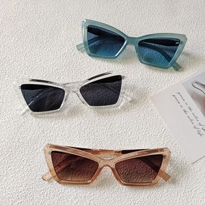 Close-up of three retro cat-eye sunglasses in blue, clear, and brown frames on white surface