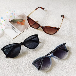 Three pairs of trendy cat-eye sunglasses in tortoiseshell and black on white background