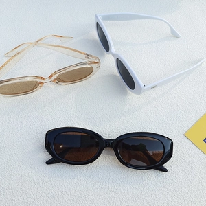 Petites lunettes de soleil ovales rétro en noir blanc et ambre sur fond blanc texturé