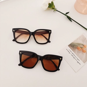 Détail de lunettes de soleil carrées avec rivets en étoile dorée et verres dégradés