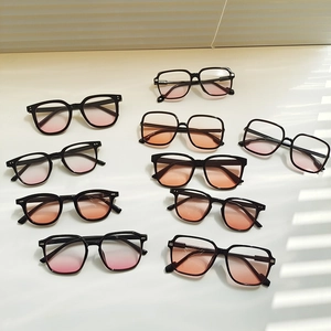 Flat lay of multiple black sunglasses featuring pink-orange gradient lenses with light shadows