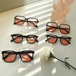 Fashionable black square sunglasses with gradient pink lenses shown in a stylish flat lay