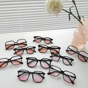 Flat lay of multiple black frame sunglasses with pink gradient lenses on white surface
