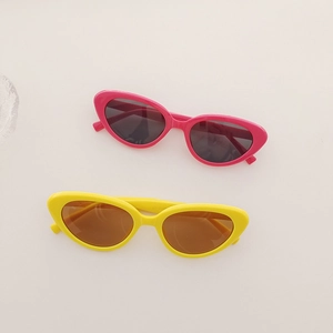 Gros plan de lunettes de soleil rétro rose et jaune pour enfants sur un fond minimaliste