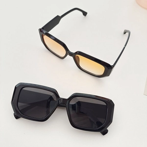 Detail of square vintage sunglasses with black frames and orange gradient lenses