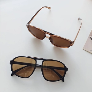 Close-up of retro double-bridge pilot sunglasses with amber and black frames for driving