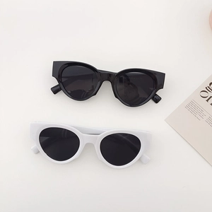 Lunettes de soleil ovales à monture épaisse en noir et blanc sur un fond minimaliste