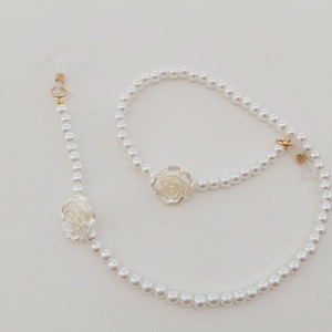 Détail de chaîne à lunettes avec breloques roses blanches et perles d'imitation