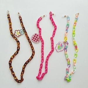 Détail de chaînes de lunettes colorées en acrylique avec breloques fleurs et cœurs
