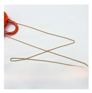 Detail of glossy red heart-shaped acrylic bag featuring a sleek golden metal chain strap