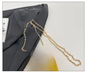 Detail of the golden octagonal mirror box bag with a metallic chain strap and clasp