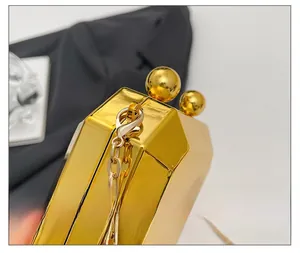 Detail of golden geometric evening bag showing polished mirror finish and sphere clasp