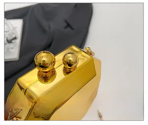 Macro view of golden geometric clutch with sphere clasps and fine metal chain detail