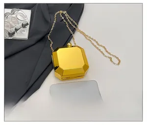Mini gold octagonal evening bag with chain shown next to a phone for size comparison