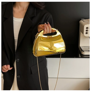 Detail of gold mirror metal party clutch with integrated handle and fine chain strap