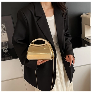Detail der goldenen Hartschalen-Abendtasche mit hohlem Griff und eleganter Metallkette