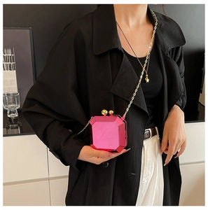 Detail of rose red octagonal gem-shaped mini bag with metallic gold chain strap