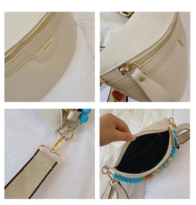 Detail view of cream pebble leather chest bag with golden hardware and colorful beaded tassel