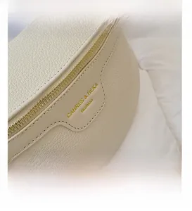 Close-up of off-white lychee pattern leather chest bag with gold zipper and branding