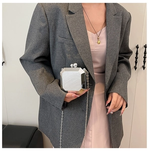 Mirror-finish silver geometric chain box bag shown with a gray plaid suit and silk dress