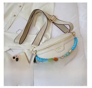 Detail view of off-white crossbody bag with colorful beads next to a smartphone for scale
