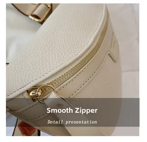 Detail view of smooth golden metal zipper and cream lychee grain leather on chest bag