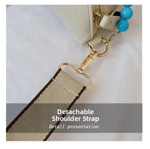 Detail of lychee pattern bag featuring beige woven strap and blue beaded accessory