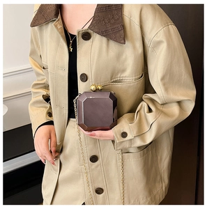 Detail of purple metallic octagonal clutch bag with golden chain and sphere clasp