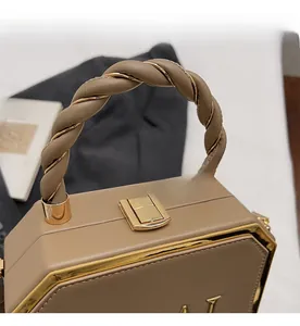 Close-up of khaki geometric handbag featuring gold hardware and a twisted handle