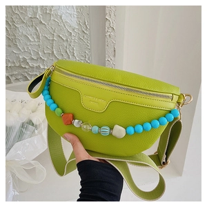 Detail of green lychee leather chest bag with decorative beads and wide nylon strap