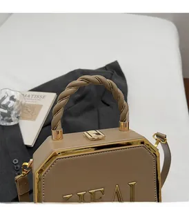Close-up of brown octagon box bag with gold metal trim and woven texture handle