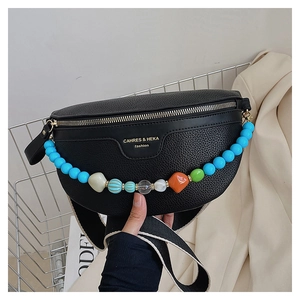 Detail of black lychee grain chest bag featuring colorful beaded chain and wide strap