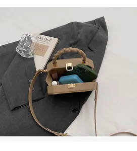 Khaki square handbag interior showing capacity for phone and cosmetics with woven handle