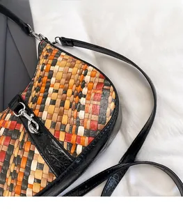 Close-up of vibrant woven crossbody bag featuring textured black leather and silver hardware