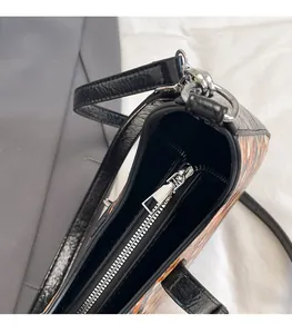 Close-up of smooth silver metal zipper and black textured leather trim on a tote bag