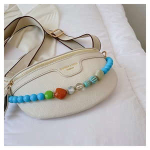 Detail of off-white lychee leather chest bag featuring vibrant colorful beaded strap detail