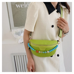 Detail of bright green crossbody bag with colorful beads on white tweed dress
