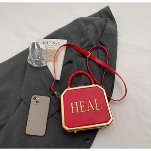 Detail of red leather octagonal handbag with gold metal frame and HEAL lettering