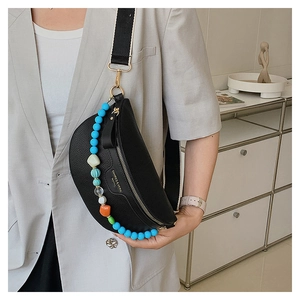 Close-up of black leather crescent chest bag with colorful bead chain and gold zipper