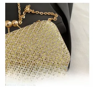 Dettaglio di una borsa da sera dorata scintillante con trama a rete e chiusura a sfera