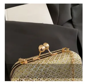 Dettaglio della chiusura sferica dorata e trama di paillettes della borsa da sera