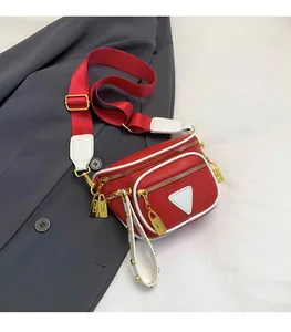 Détail du sac banane rouge avec bordure blanche, accents dorés et breloques décoratives