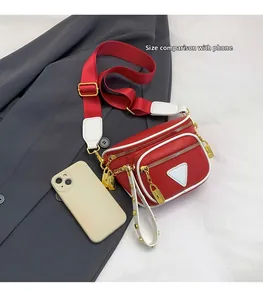 Détail du sac banane rouge et blanc avec verrous dorés à côté d'un téléphone pour échelle