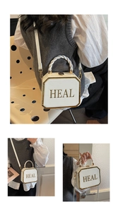 Close-up of ivory octagon box bag with golden metal frame and woven twisted handle