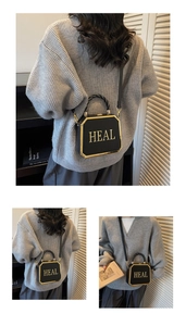 Detail of octagonal crossbody bag with gold HEAL lettering and woven top handle